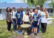 Photo of group of adults and students behind a concrete bird bath.