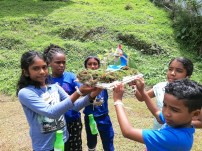 Photo of a group of children displaying their completed Bee Hummingbird habitat with flowers for the bird to feed on and a water source.
