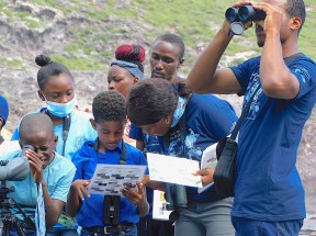 Ajhermae White helps students of the Grade 5 class of Look Out Primary School with shorebird ID during their field trip at Marguerita Bay. (Photo by Stephen Mendes)