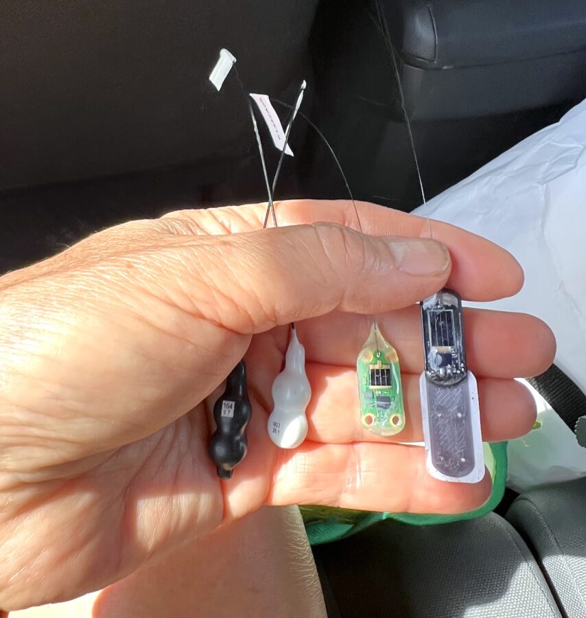 Photo of various Motus tags held in the palm of a hand.