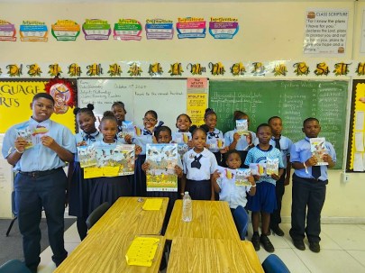Group photo of students in front of a class. They are standing and holding WMBD posters.